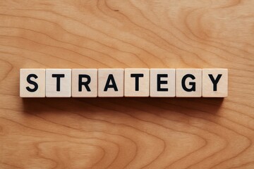 Poster - An overhead view wooden blocks arranged to spell strategy on a maple desk symbolizing business decision-making and planning