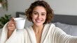© Nataliya - Happy young woman with curly hair smiling and holding a white mug indoors
