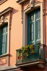 Aufkleber - A pink building with a green door and balcony, perfect for residential or commercial use
