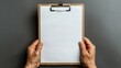 © PhotoMax - Person grasping clipboard with empty sheet of paper against a clean white background