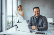 © Dragana Gordic - Smiling Business Professional Working on Laptop in a Modern Office Setting