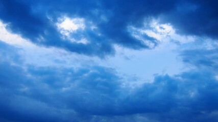 Poster - Witness the beautiful transformation of a sky dominated by blue clouds, creating a captivating dance of color and light as daylight fades into evening. Nature artistry unfolds before your eyes