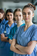 © Starmarpro - A portrait of four young female healthcare professionals in blue scrubs stands in a line, their arms crossed. They appear to be ready to work hard and are showing commitment.