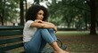 © Margarita Ratatosk - Young woman with curly hair sitting alone on a park bench, her posture shows signs of mental discomfort, concept of mental disorder.