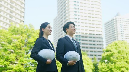 Aufkleber - 新緑の街の前にヘルメットを持って立つビジネスパーソンのグループ