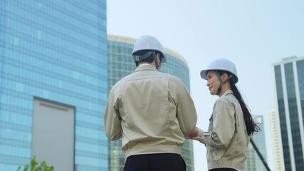 Poster - 建設現場でタブレットを見ながら打ち合わせする男女エンジニアのグループ