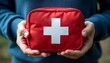 © Wool World - A person holding a red first aid kit with a white cross on it