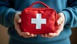 © Wool World - A person holding a red first aid kit with a white cross on it