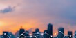 © Uro - Blurred city skyline at sunset with a digital network overlay in the foreground.