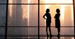 © Stock Pix - Two women silhouetted against a cityscape view, discussing plans during golden hour. They stand in front of large office windows.