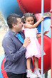 © Arlette - Divorced single dad spends time with his 4-year-old Latina daughter on the playground equipment at the park during the weekend to celebrate Father's Day