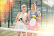 © JackF - Mature smiling female padel player with her young daughter standing ready for game in court