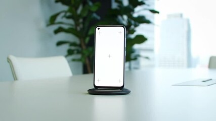 Poster - Smartphone with Blank White Screen on Conference Table with Green Plants and Blurred Office Building Background
