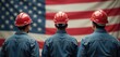 © miss irine - Three workers in hard hats against American flag. Men stand back to camera, wear red helmets, denim jackets. Construction industry workers on Labor Day. Patriotism, national holiday. Blue collar