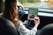 © miss irine - Unrecognizable woman driving modern electric car. tablet displays navigation system with red car image. Female driver holds smoothie. Future tech auto trip.