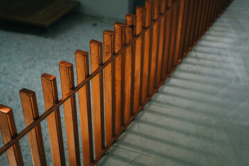Poster - Modern Copper Colored Vertical Metal Fence with Shadows Casting on Smooth Surface in Urban Environment