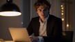 © Abdul - Photogenic European male in his 20s sitting at a desk with a laptop focused on work indoor lighting highlighting his sharp features isolated background