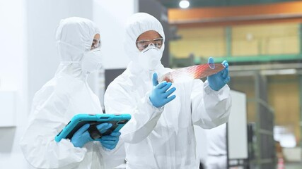 Poster - 半導体工場でタブレットを持ってシリコンウエハーを検査する防護服を着た男女作業員