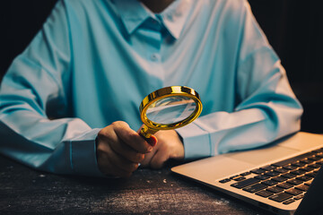 Poster - businessman working. person holding magnifying glass while working on laptop in dark environment wit
