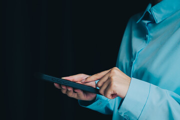 Poster - Smartphone concept. Close-Up of Person in Blue Shirt Using Smartphone with Finger on Screen in Dark Background