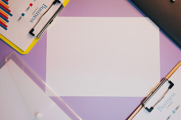 Poster - Flat lay of Blank Document on Colorful Desk Surrounded by Business Charts and Clipboards for Project Planning and Organization