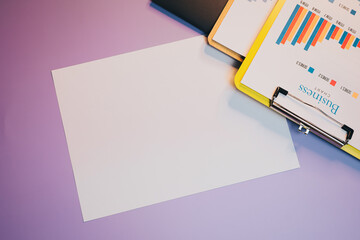 Poster - Flat lay of Blank sheet of paper and clipboard with graphs on purple background for business, planning, and creativity
