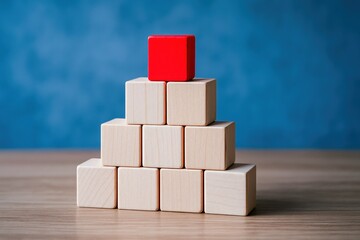 Poster - A red cube atop a pyramid wooden blocks symbolizes business strategy and leadership in decision-making for growth and innovation