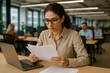 © Firuza - Woman sitting at table with laptop and papers.