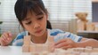 © FAMILY STOCK - Young Asian girl focused on stacking wooden blocks, promoting STEM learning, creativity, and motor skill development. Concept of early education, problem solving, and cognitive growth.
