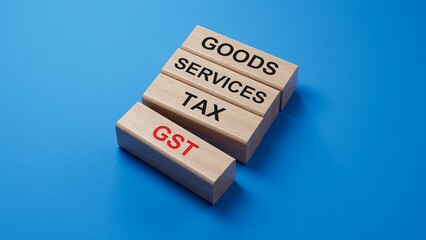 Poster - GST - Goods Services Tax symbol. Concept word GST on wooden blocks. Business and GST concept. Copy space.3D rendering on blue background.
