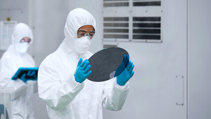 Poster - 半導体工場でシリコンウエハーを検査する防護服を着た男性作業員