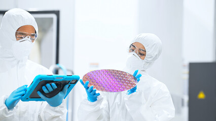 Poster - 半導体工場でタブレットを持ってシリコンウエハーを検査する防護服を着た男女作業員