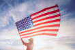 © Vladimir Razgulyaev - Close up on USA flag in a hand of a person against the sky. Independence Day or travelling in America concept.
