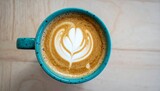 Close-up of a hot cappuccino cup with a heart design on a white saucer, perfect for a cafe breakfast