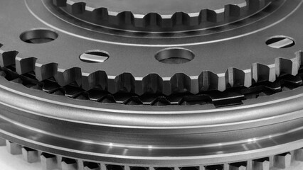 Poster - Dark black close-up of black gear with many holes. Gear is part of a larger set of gears, industrial precision concept background