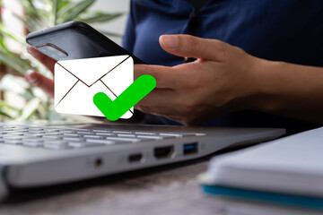 Poster - A woman's hands working on a laptop and her cell phone with an email envelope icon and a green check mark. Concept of checked email.