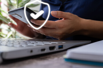 Poster - Woman's hands working on laptop and her cell phone with shield icon with check mark