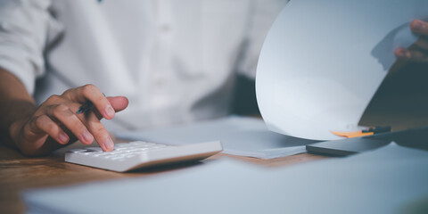 Aufkleber - Businessman calculating figures in company financial documents with a calculator,analysis of company financial data,Planning to assess and review budgets,concept of finance and investment.