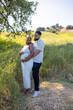 © Bogdan Pictures - In a vibrant summer filled with warmth, a loving African American couple embraces, joyfully celebrating their pregnancy and showcasing their emotional connection in natures beauty
