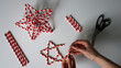 © Lesia - Hand made. Female hands holds needle with thread. In the process of making Christmas stars from paper tubes for cocktails. Tubes in red, white stripe. Scissors, white thread. White background. Photo