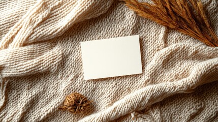 Poster - Soft flat lay of blank cream card placed over warm, textured knitted fabric
