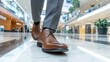 © PaulShlykov - Close-up of a man's brown leather dress shoes walking in a modern shopping mall