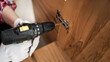 © Andrii Lysenko - Handyman using electric drill for fixing hinges while doing furniture assembly. Carpentry Concept.