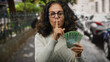 © Krakenimages.com - Middle-aged woman holding russian rubles gesturing silence on a city street with cars in the background.