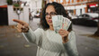 © Krakenimages.com - Middle-aged woman on city street holding czech koruna banknotes with determination, pointing at something significant.