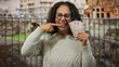 © Krakenimages.com - Middle-aged woman in rome points to her teeth while holding uae dirham banknotes, set against a backdrop of city street and ancient roman ruins.