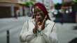 © Krakenimages.com - African american woman celebrating with a joyful expression outdoors in a city street setting, wearing glasses and medical attire, symbolizing success and happiness.