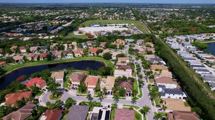 Aerial footage of canal side properties in sunny residential area with boat access