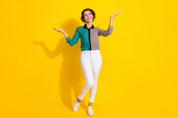 Poster - Photo of positive nice lovely girl wear trendy print clothes hold demonstrate empty space isolated on yellow color background