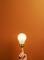 Poster - Illuminated light bulb balanced on fingertip against brown background for innovation, business, and creative promotion concept templates.
